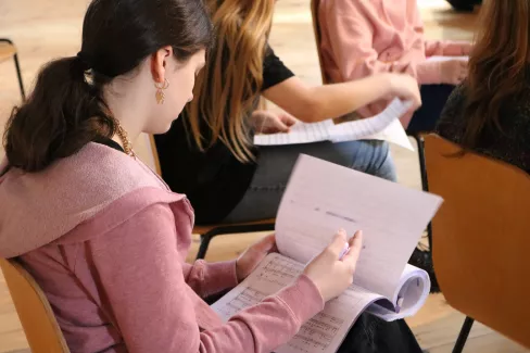 Sängerin ist von hinten zu sehen mit einem Notenblatt in der Hand