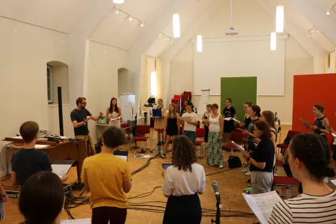 Der gesamte Chor und Chorleiter Daniel Barke sind zu sehen während einer Probe