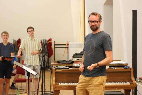 Chorleiter Daniel Barke spielt Luftgitarre während der Probenphase im Sommer 2022