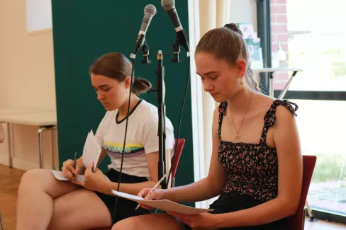 Zwei Sängerinnen der Young Voices machen sich während einer Probe Notizen in ihre Noten